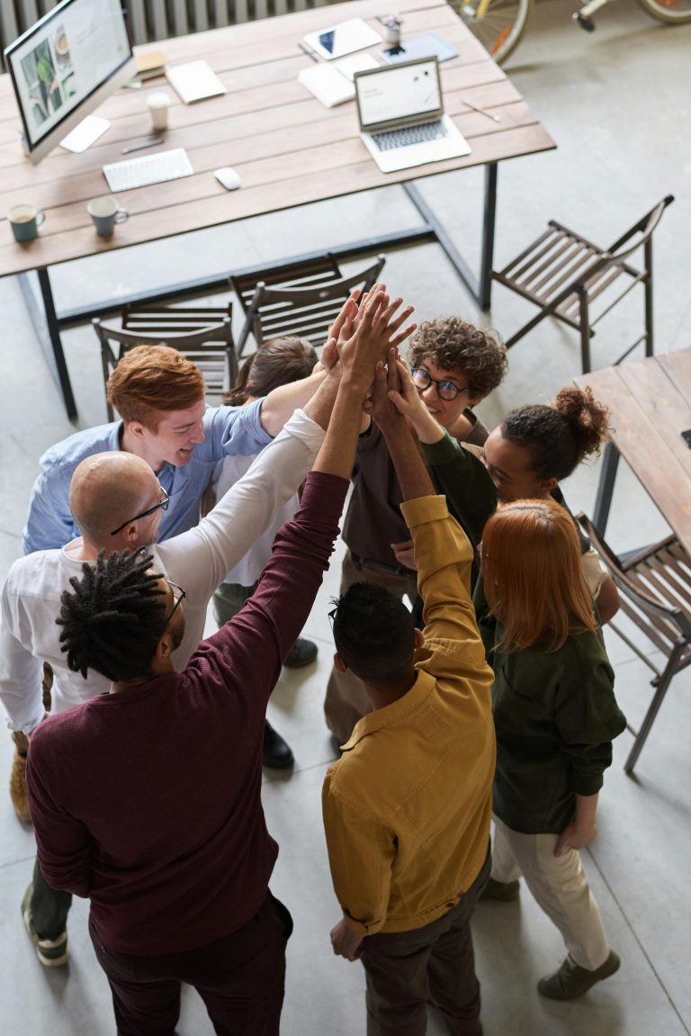 Home % A diverse group of professionals high-fiving in a modern office, showcasing teamwork and collaboration.